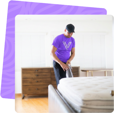 Mover preparing a mattress for transport in a bedroom